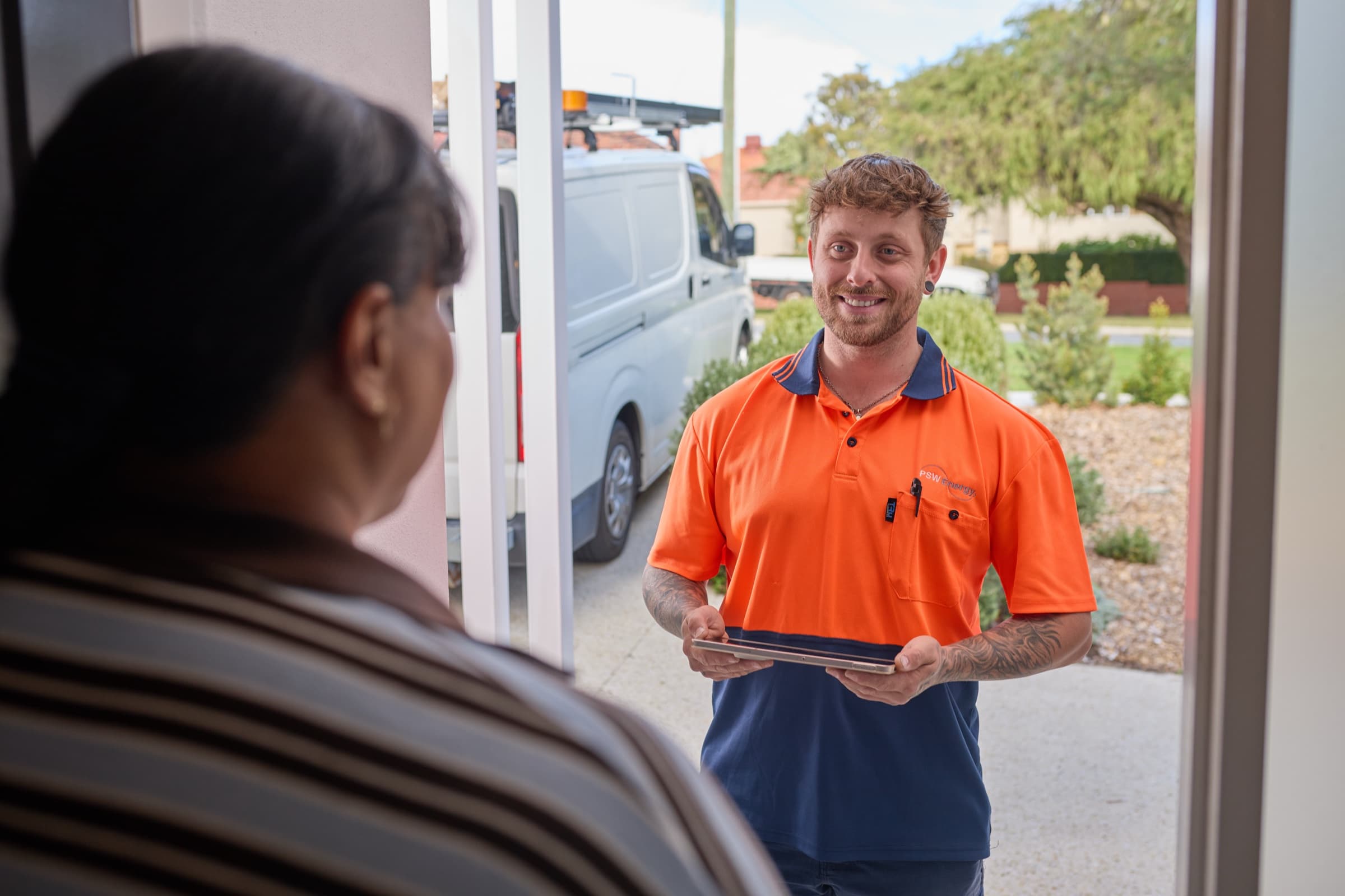 Daniel Kohn speaking with a customer at their front door, holding a tablet.