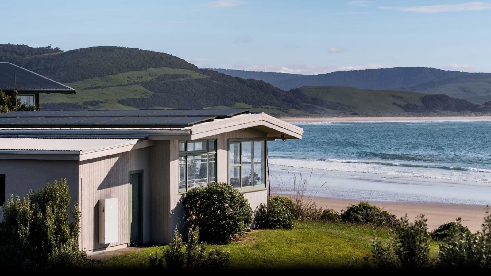 Rooftop solar and a wall-mounted home battery on a coastal house