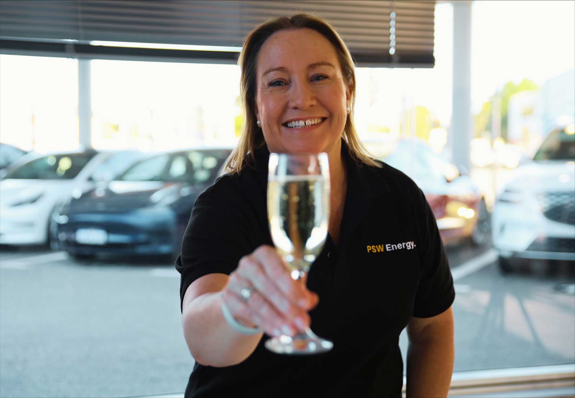 Kate Rutherford pictured holding a glass of champagne for the Tesla Energy Performance Excellence Award